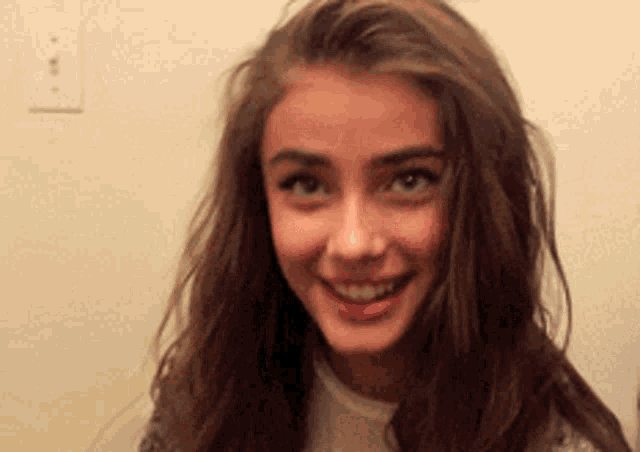 a young woman with long brown hair is smiling and looking up .
