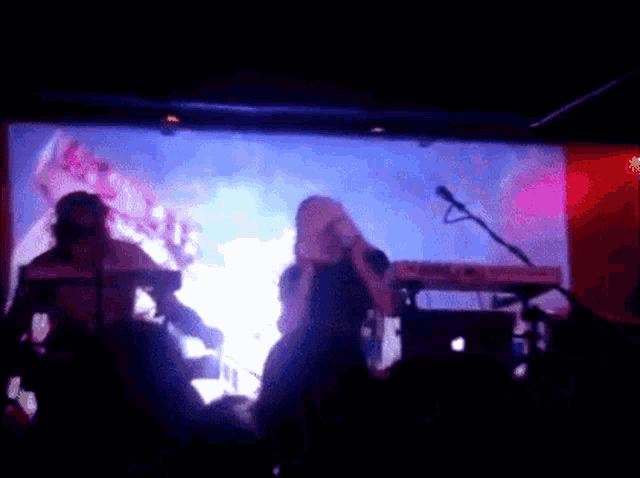 a woman singing into a microphone in front of a crowd
