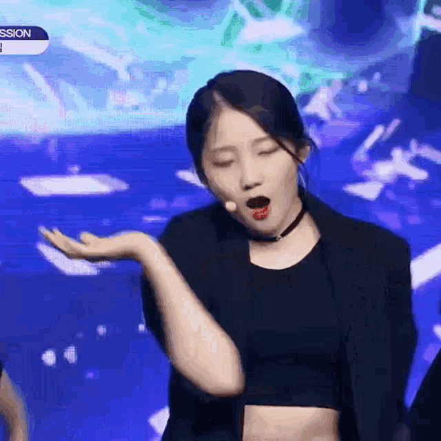 a woman in a black crop top and jacket is dancing on stage