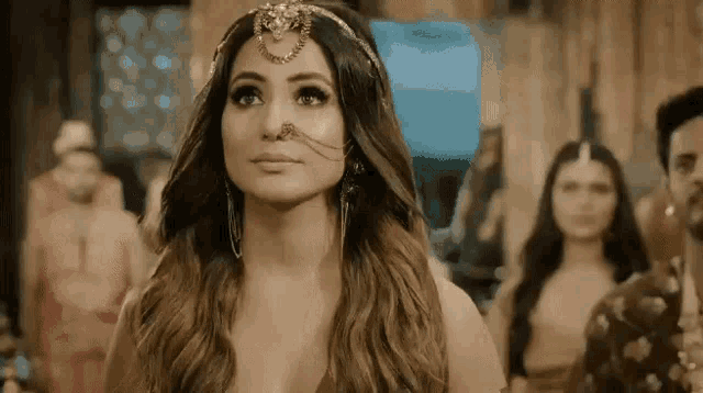 a woman wearing a nose ring and earrings is standing in front of a crowd of people .