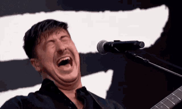 a man is singing into a microphone while playing a guitar .
