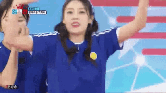 a woman in a blue soccer jersey is dancing on a stage with her hands in the air .