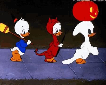 three cartoon ducks dressed in halloween costumes are walking down the street .