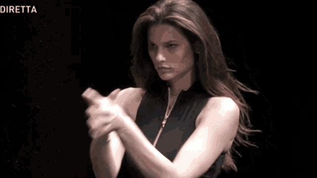 a woman in a black dress is clapping her hands in front of a black background with the word diretta on it