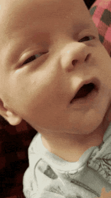 a close up of a baby 's face with his mouth wide open