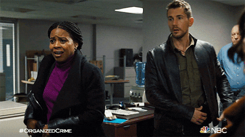 a man and a woman are standing next to each other in an office with the nbc logo on the bottom right