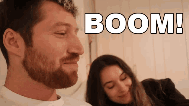 a man with a beard and a woman behind him with the words boom written above him