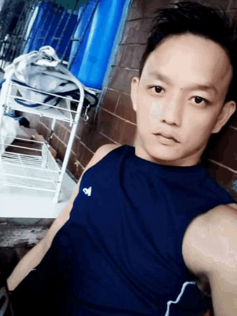 a man wearing a blue adidas tank top is taking a picture of himself