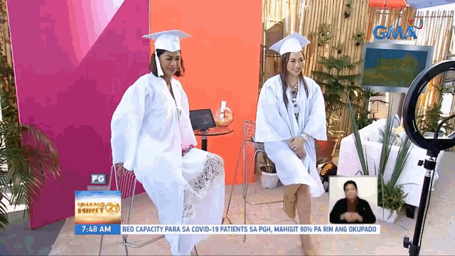 two women in graduation gowns are on a gma news show