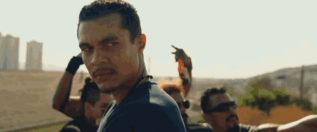 a man is standing in front of a crowd of people and looking at the camera .