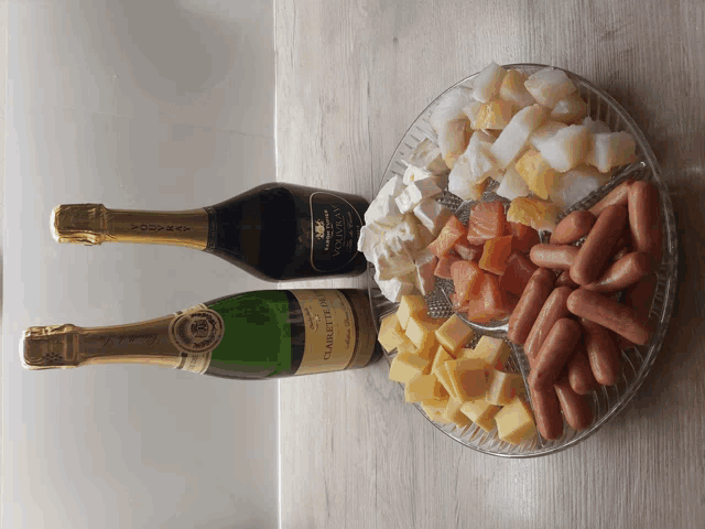 two bottles of champagne sit next to a plate of food