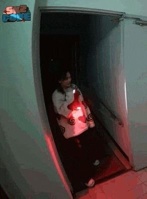 a woman is walking through a dark hallway holding a flashlight .