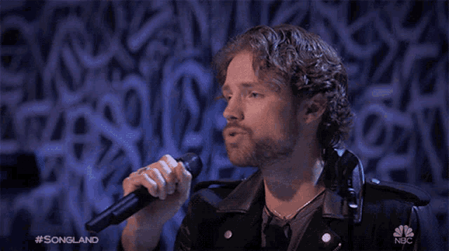 a man singing into a microphone with #songland on the bottom