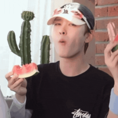 a man wearing a hat is eating a slice of watermelon