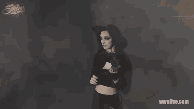 a woman in a black crop top stands in front of a wwnlive.com banner