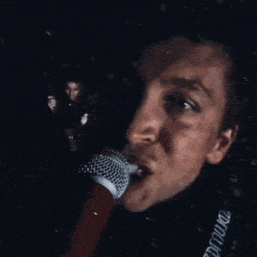 a man singing into a microphone with a red cup in front of his face