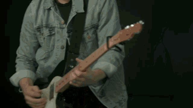 a man is playing a guitar in front of a microphone and singing into it .