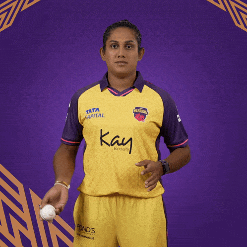 a woman wearing a yellow and purple shirt that says kay beauty on it