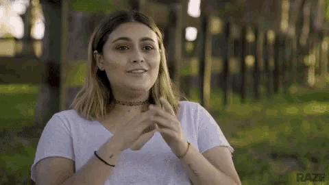 a woman in a white t-shirt is clapping her hands .
