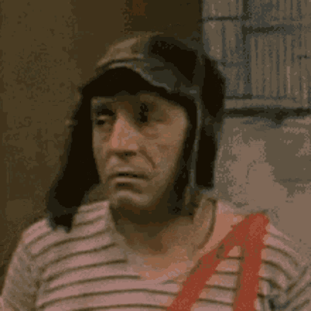 a close up of a man wearing a hat and overalls .