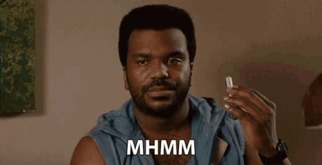 a man with a beard is holding a glass of water and saying mhmm .