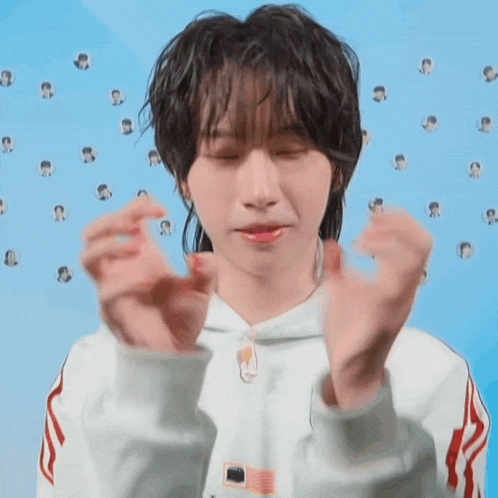 a young man with a ponytail is making a heart shape with his hands .
