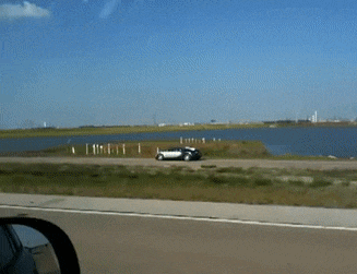 a car is driving down a road near a lake