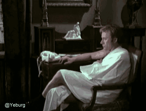 a man in a white robe is sitting in a chair with a phone in front of him