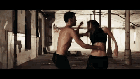 a man without a shirt is holding a woman in a dark room .