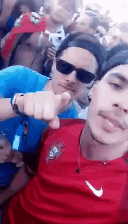 two men are posing for a picture in front of a crowd of people .