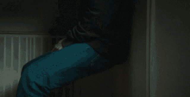 a man is sitting in a dark room with his legs crossed .