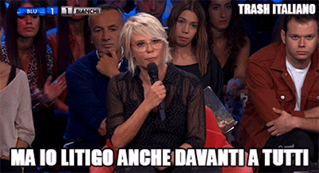 a woman speaking into a microphone in front of a crowd with the words trash italiano written below her