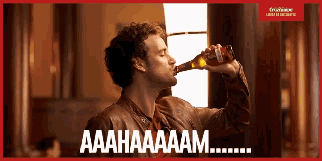 a man is drinking from a bottle of cruzcampo