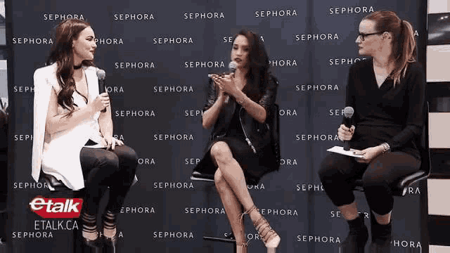 three women sitting in front of a sephora wall