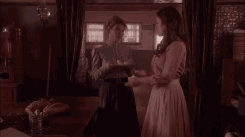 a woman in a pink dress is holding a plate of food in a kitchen .