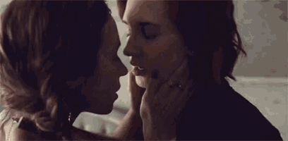 a couple of women are kissing each other in a room .