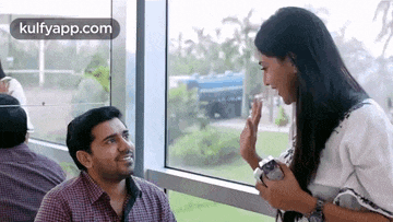 a man and a woman are sitting in front of a window .