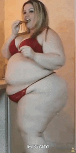 a very fat woman in a red bra and red bikini is eating something .