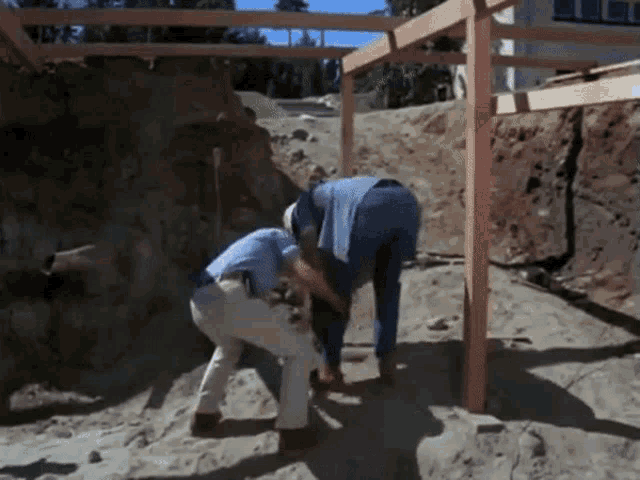 a couple of men are working on a wooden structure