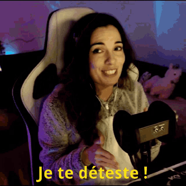 a woman is sitting in front of a microphone with the words je te deteste written on the bottom