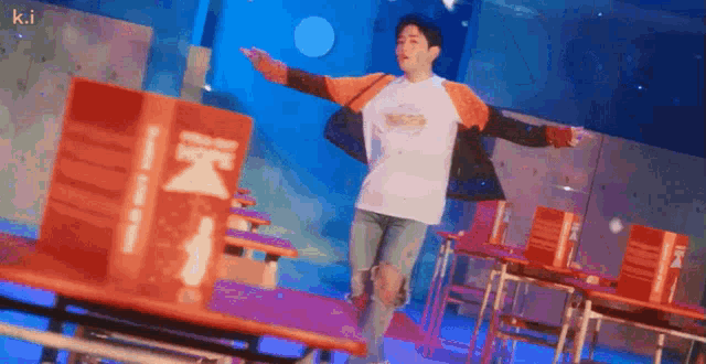 a man is standing in front of a table with his arms outstretched and a box in the background .