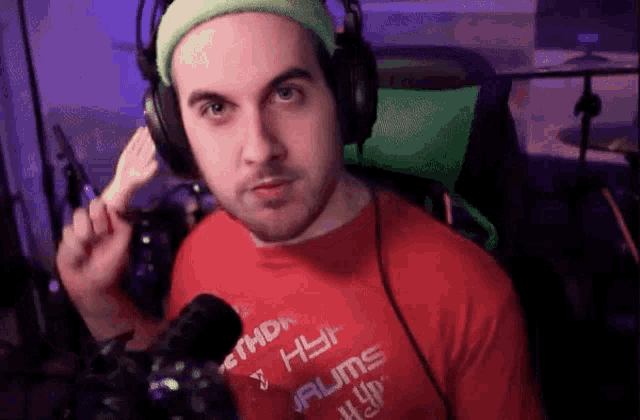 a man wearing headphones and a red shirt that says ' drums ' on it