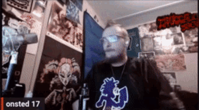 a man wearing glasses and a shirt that says onsted 17 looks at the camera