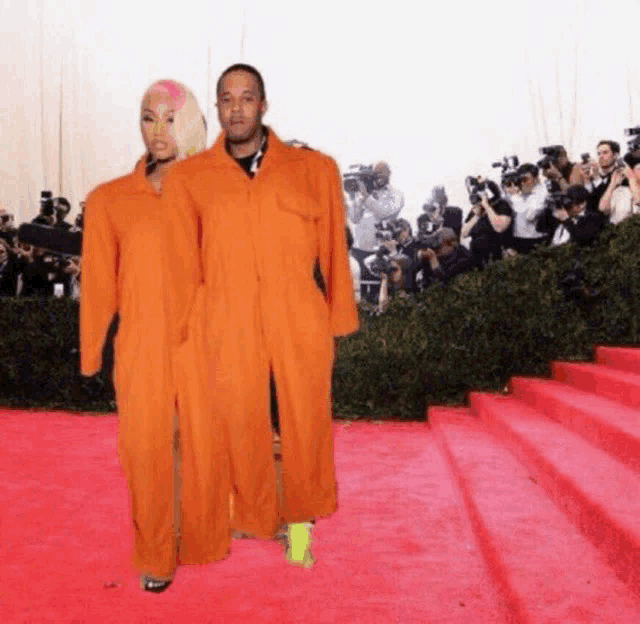 a man and a woman are standing on a red carpet