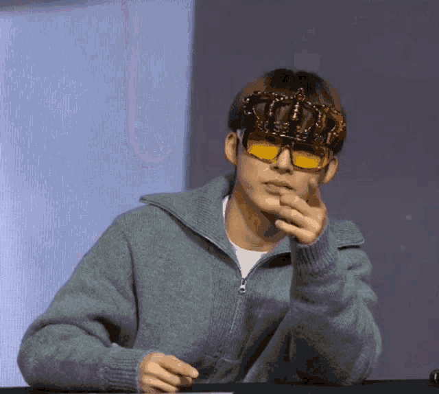a man wearing a sweater and sunglasses with a crown on his face