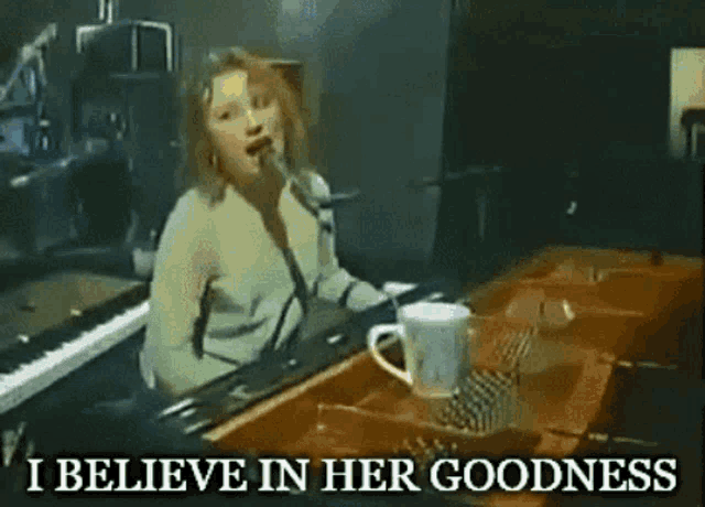 a woman singing at a piano with the words i believe in her goodness
