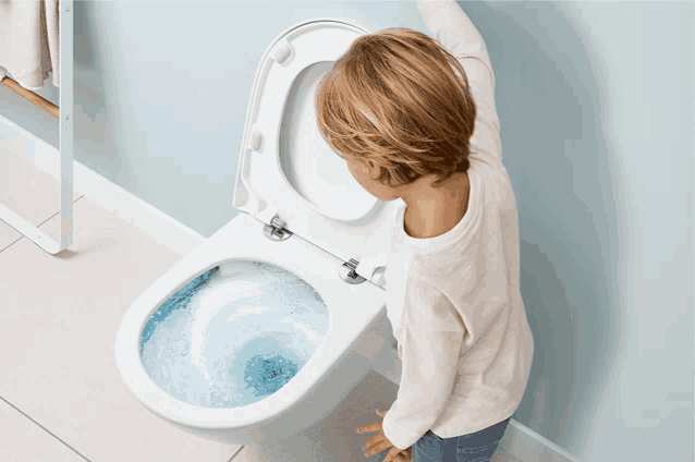 a young boy is looking into a toilet with the lid open