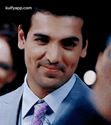 a man in a suit and tie is smiling while looking at the camera .