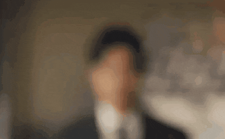 a blurry picture of a man in a suit and tie covering his face