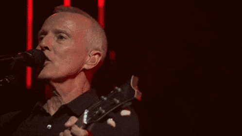 a man is singing into a microphone while playing a guitar